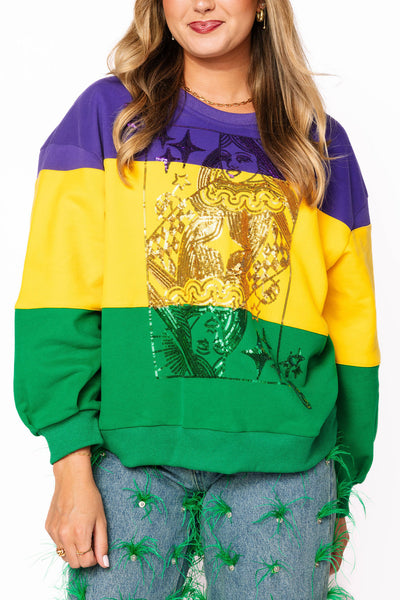“Purple, yellow, and green color-blocked Queen of Sparkles sweatshirt with large sequin Queen playing card graphic.”
