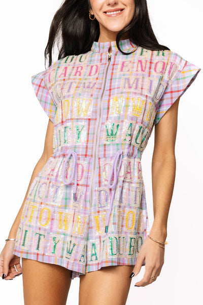 “Lavender plaid Queen of Sparkles romper with multicolor sequin street tile lettering, zip-front design, cap sleeves, and drawstring waist.”