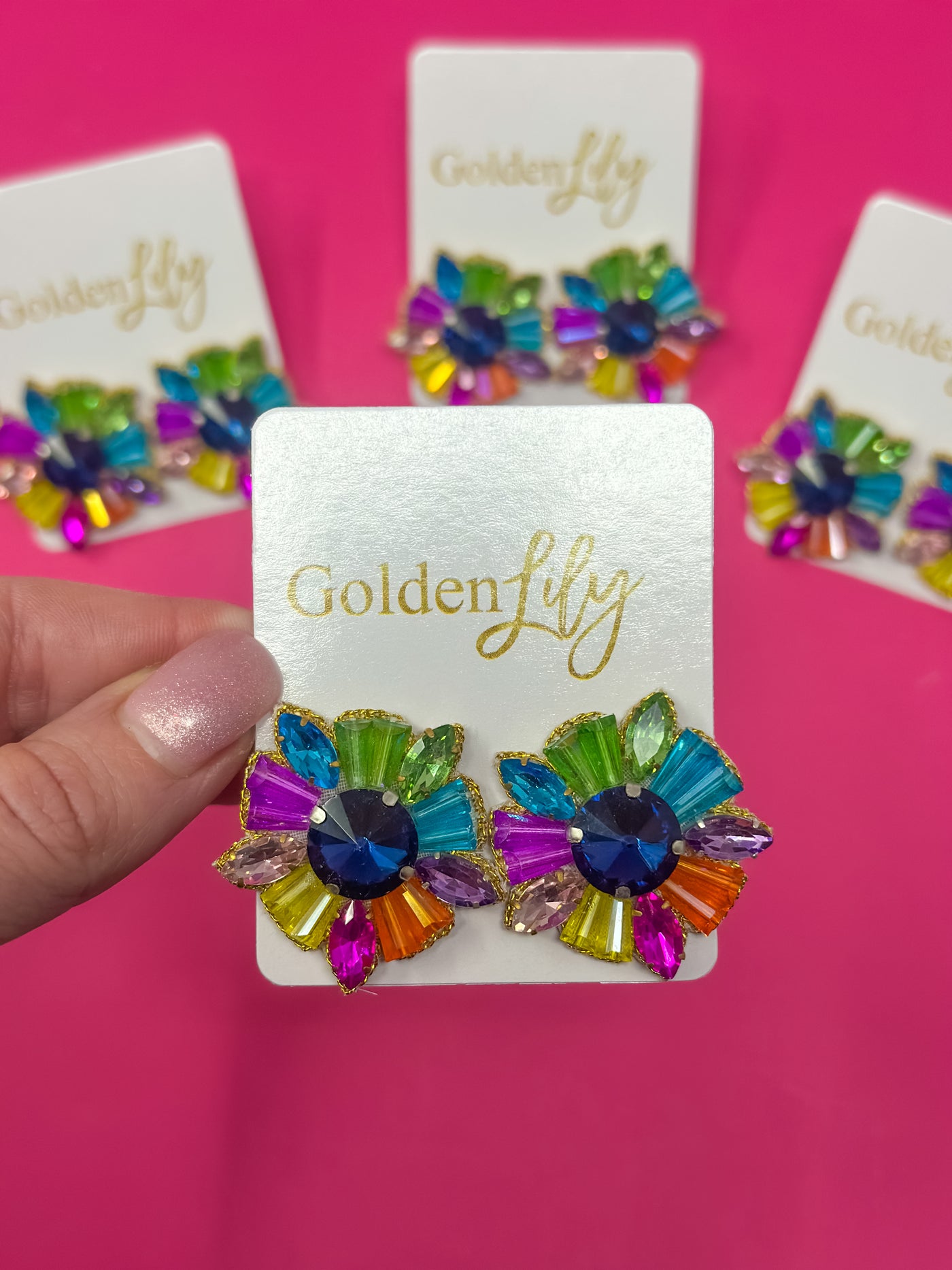 Colorful rhinestone burst earrings with blue center and multi-colored gems on Golden Lily card.